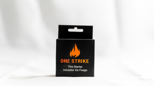 Black packaging of 'One Strike' fire starter with orange flame logo on a white background
